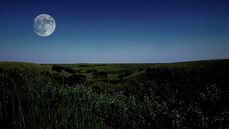 The Full Moon Rises Above A Hilly Prairie Landscape On A Summer Evening