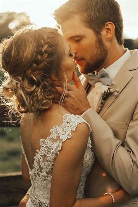 A Bride And Groom Kissing Each Other In Front Of The Sun At Their