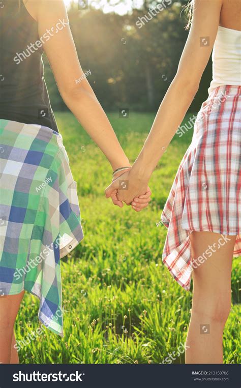 Two Female Friends Holding Hands In Summer Stock Photo