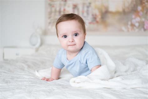 Cute Baby Babe Months Old In Blu Bodysuit Smiling And Lying On Bed With White Plaid At Home