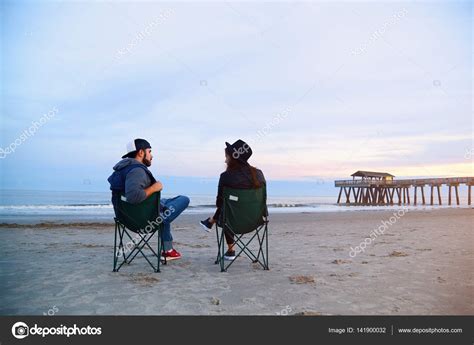 Paar Sitzt In Liegestühlen Am Schönen Sonnenuntergang Strand Stockfotografie Lizenzfreie
