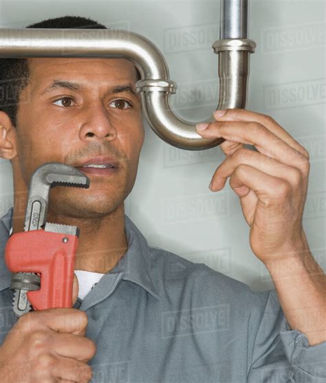 African Male Plumber Holding Wrench Next To Pipe Stock Photo Dissolve