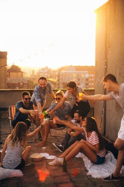 A Group Of People Sitting On Top Of A Roof Next To Each Other Holding Wine Glasses