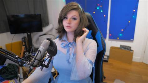 A Woman In A Blue Dress Sitting At A Desk With A Microphone And Headphones