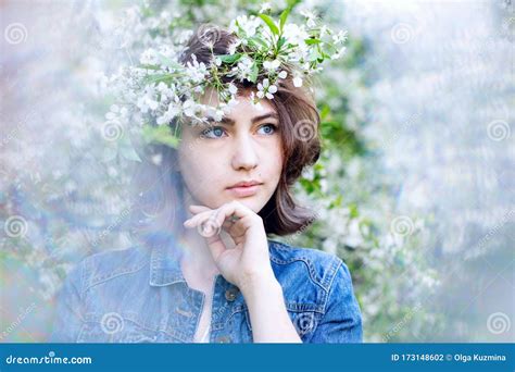 a cute girl of european appearance with a wreath on her head in a denim jacket on a background
