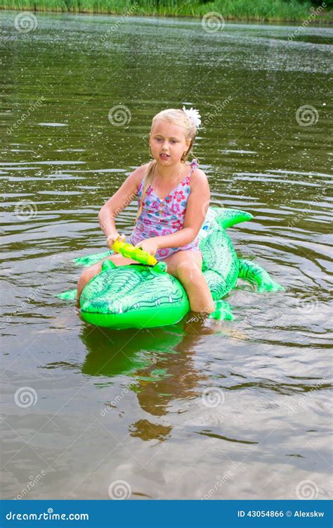 Girl Swimming In The River With Inflatable Crocodile Stock Photo
