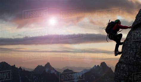 Caucasian Climber Scaling Mountain In Remote Landscape Stock Photo