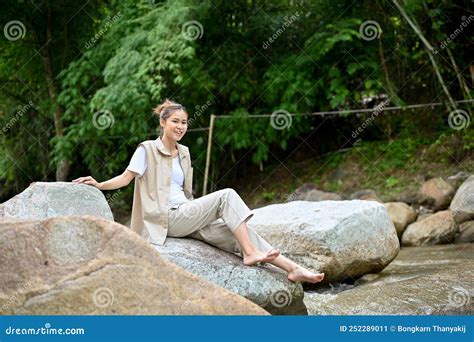 Happy Asian Female Camper Traveler Sitting On A River Rock Near The The