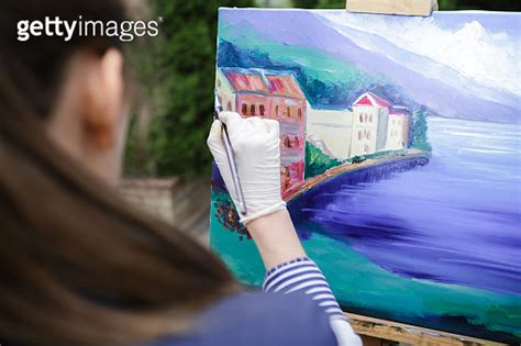 Woman Artist With A Brush In Her Hand Draws On Canvas