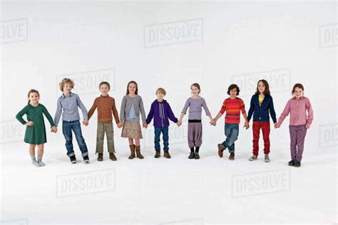 A Group Of Kids Standing In A Row And Holding Hands Stock Photo