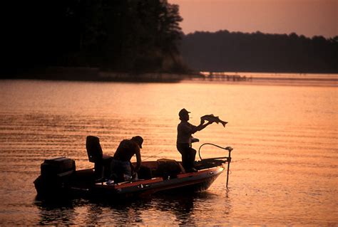 Silhouette Of Two Men In A Fishing Boat On A Lake At Sunset Stockyard