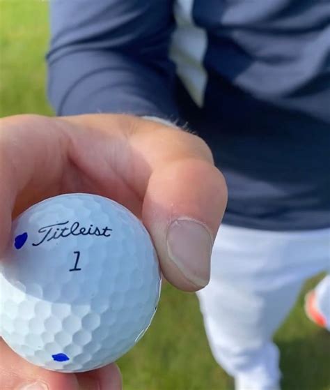 A Close Up Of A Person Holding A Golf Ball With The Number 1 On It