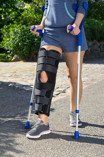 Woman Wearing A Leg Brace Walking On Crutches Stock Photo Download