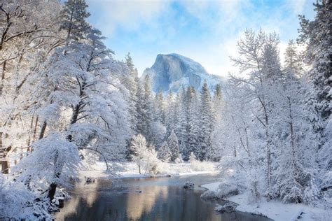 A River Surrounded By Snow Covered Trees In Front Of A Tall Mountain
