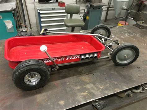 A Red Wagon Sitting On Top Of A Metal Table In A Garage Next To Other Tools