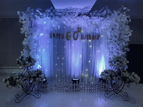 The Backdrop Is Decorated With White Flowers And Lights