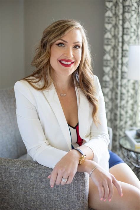 A Woman Sitting On Top Of A Couch Wearing A White Blazer And Red Tie