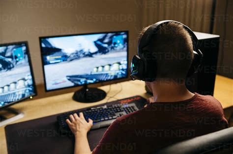 Young Man Playing Video Games With Computer At Desk Stock Photo