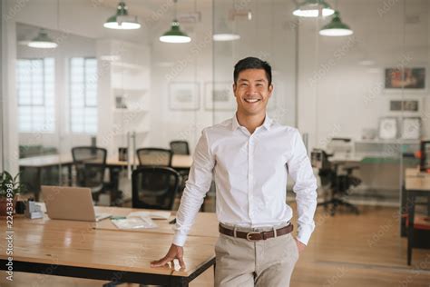 Young Asian Businessman Standing In An Office Smiling Confidently Stock