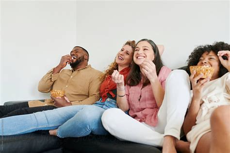 Diverse Group Of Laughing Friends Sitting Together On A Sofa At Home