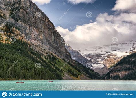 Tourists Canoeing On Turquoise Lake With Rocky Mountains In Lake Louise