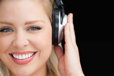 Premium Photo Smiling Blonde Woman Listening To Music Through Headphones