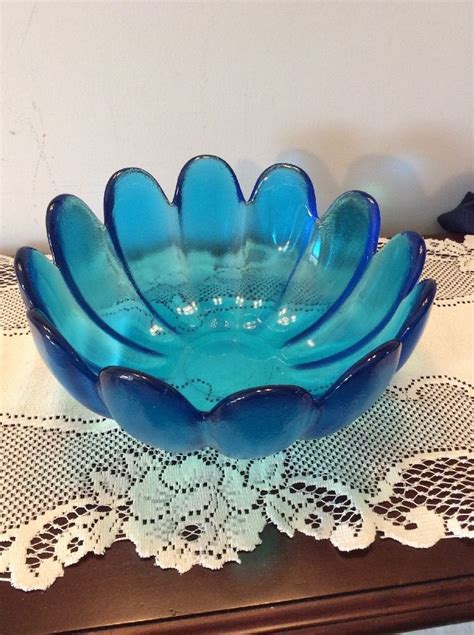 A Blue Glass Bowl Sitting On Top Of A Table Next To Doily And Lace