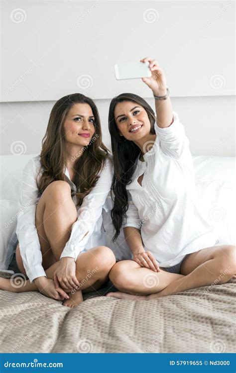 Two Hot Girls Lying On A Bed Taking A Photo Of Themselves With Stock Image Image Of Fashion