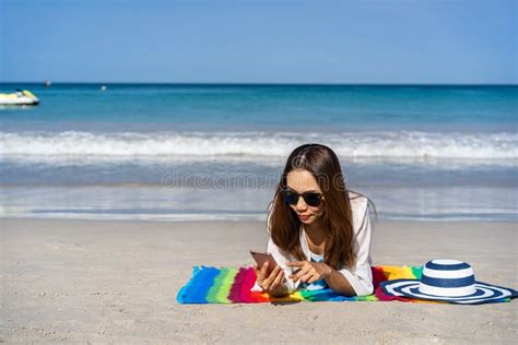 Young Asian Woman Traveler Using Her Smartphone And Sunbath At Tropical