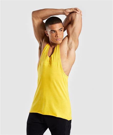 A Man In Yellow Tank Top Posing With His Hands On His Head And Arms Behind His Head