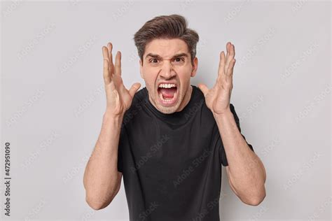 Outraged Young Man Yells Angrily Keeps Mouth Opened Raises Hands Being
