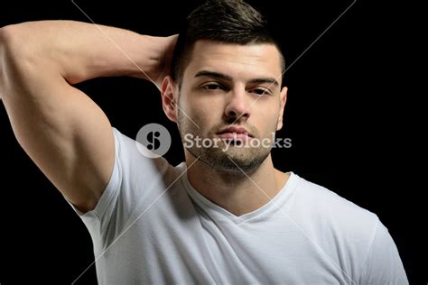 Handsome Young Man Posing With His Hand Behind His Head On Black
