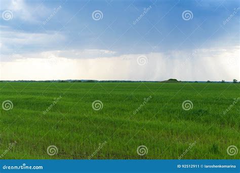 A Large Storm Cloud Over A Wide Green Agricultural Field In The