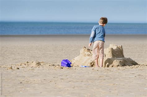 Child Building A Large Sand Castle On The Beach Del Colaborador De