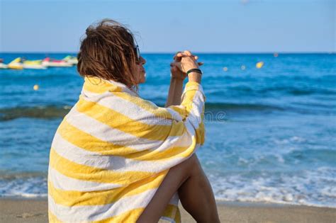 Mature Woman Sitting On Seashore Resting Beautiful Female With Beach Towel On Her Shoulders