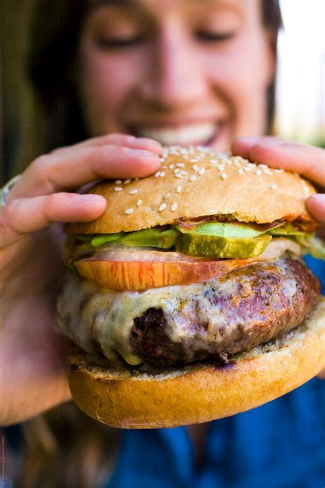 Smiling Girl Eats Burger By Stocksy Contributor Sara Remington