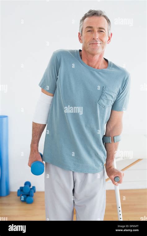 Smiling Mature Man With Crutch And Dumbbell Stock Photo Alamy