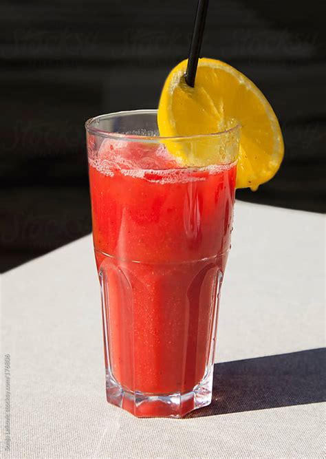 glass of fresh strawberry juice with lemon slice by sonja lekovic stocksy united