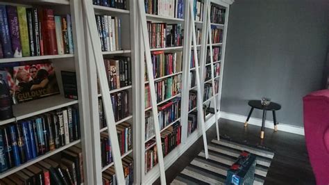 A Book Shelf Filled With Lots Of Books Next To A Pink Chair