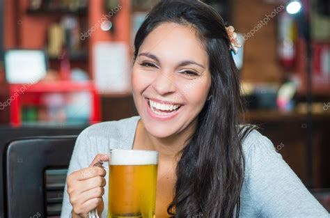 Brunette Model Sitting By Restaurant Table Holding Glass Of Beer And
