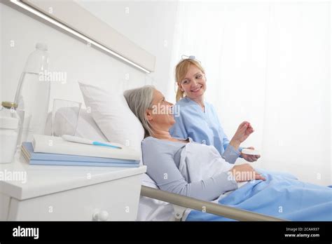 Nurse Gives The Pill To The Elderly Woman Patient Lying In The Hospital