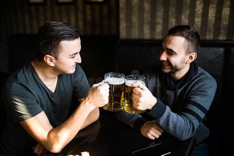 Two Young Man Sitting In Pub Eating And Drinking Beer At Pub Stock