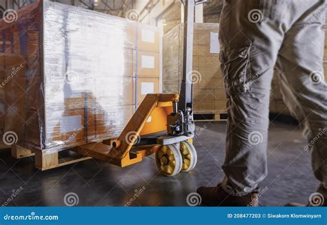 Warehouse Worker Working With Hand Pallet Jack Unloading Cargo Boxes At The Warehouse Storage