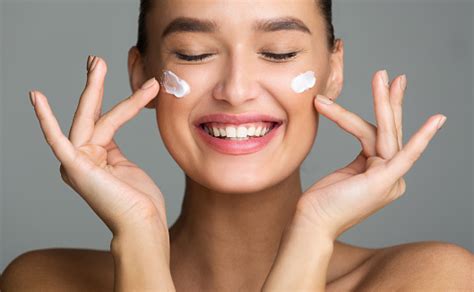 Happy Woman Applying Cosmetic Cream On Her Face Stock Photo Download