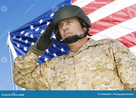 Confident Soldier Saluting In Front Of American Flag Stock Photo