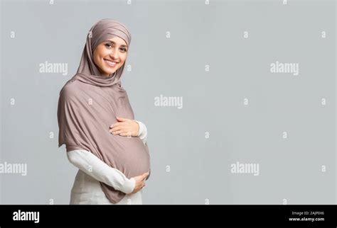 Pregnancy And Islam Concept Beautiful Pregnant Muslim Woman In Hijab Touching Her Belly Posing