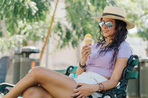Premium Photo A Woman Sits On A Bench In A Park And Eats An Ice Cream Cone