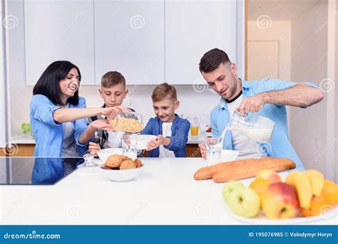 mom dad and two sons eating healthy morning breakfast with cornflakes and fresh milk on cozy