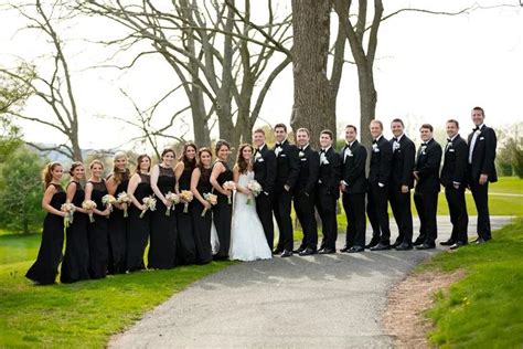a large group of people in formal wear posing for a photo on the side of a road