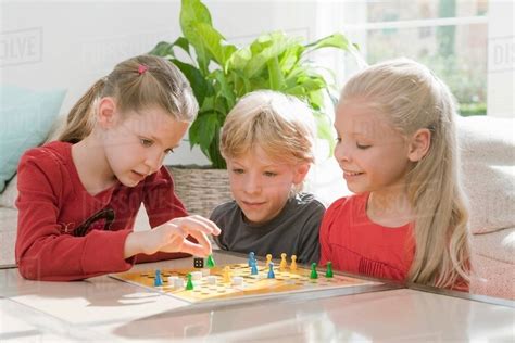 Three children playing a board game - Stock Photo - Dissolve